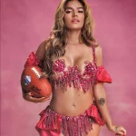 Karol G - Eine Frau in einem rosafarbenen Outfit versprüht Karol G-Vibes, während sie einen Fußball hält, bereit für ihren eigenen Halftime-Show-Moment. Diese Beschreibung wurde mit der FootballR KI automatisch generiert.