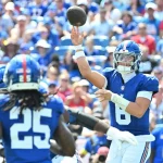Ein Football-Quarterback in einem blauen Trikot (#8) wirft einen Pass während eines NFL Preseason Spiels. Ein anderer Spieler in Blau (#25) läuft im Vordergrund, während die Fans, viele in Blau gekleidet, die Sitze im Stadion füllen und das Geschehen aufmerksam verfolgen. Diese Beschreibung wurde mit der FootballR KI automatisch generiert.