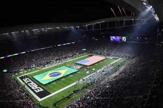 Rio de Janeiro - Ein volles Football-Stadion bei Nacht, in dem ein Spiel der NFL International Series stattfindet, mit großen brasilianischen und amerikanischen Flaggen auf dem Spielfeld. Feuerwerkskörper erhellen den Himmel, während "EAGLES" die Endzone markiert, und Zuschauer aus Brasilien füllen die beleuchteten Tribünen. Diese Beschreibung wurde mit der FootballR KI automatisch generiert.