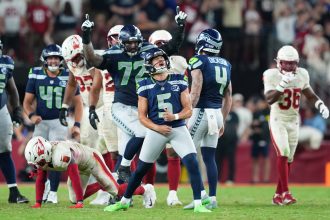 Ein Spieler der Seattle Seahawks, Jason Myers, feiert nach einem Field Goal in letzter Sekunde auf dem Spielfeld ausgelassen, ballt die Fäuste und blickt nach oben. Mannschaftskameraden und Spieler der Arizona Cardinals umringen ihn; die Emotionen kochen auf beiden Seiten hoch. Diese Beschreibung wurde mit der FootballR KI automatisch generiert.