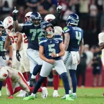 RTL TV Plan Woche 6 - Ein Spieler der Seattle Seahawks, Jason Myers, feiert nach einem Field Goal in letzter Sekunde auf dem Spielfeld ausgelassen, ballt die Fäuste und blickt nach oben. Mannschaftskameraden und Spieler der Arizona Cardinals umringen ihn; die Emotionen kochen auf beiden Seiten hoch. Diese Beschreibung wurde mit der FootballR KI automatisch generiert.