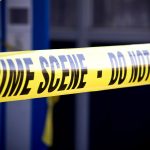 Nahaufnahme von leuchtend gelbem Tatortband mit der Aufschrift "CRIME SCENE - DO NOT ENTER". Das Klebeband markiert den eingeschränkten Zugang, mit einem unscharfen Gebäude und mehr gelbem Klebeband im Hintergrund, wo Mark Sanchez Berichten zufolge in der Nähe eines Krankenhauses festgenommen wurde. Diese Beschreibung wurde mit der FootballR KI automatisch generiert.