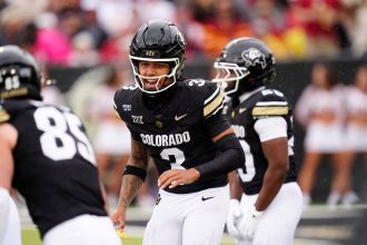 Kaidon Salter - In Week 7 des College Footballs ruft ein Spieler der Colorado Buffaloes, Nummer 3, im schwarzen Trikot ein Play aus. Umgeben von Teamkollegen, darunter Nummer 85, hebt er sich vor der unscharfen Kulisse der jubelnden Fans hervor. Diese Beschreibung wurde mit der FootballR KI automatisch generiert.