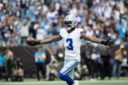 George Pickens, Dallas Cowboys, der die Trikotnummer 3 trägt, feiert mit ausgestreckten Armen, während er einen Football in der Hand hält, umgeben von einer unscharfen Menschenmenge in einem Stadion - vielleicht nach einem großen Spielzug oder einer gerüchteweisen Vertragsverlängerung mit den Cowboys. Diese Beschreibung wurde mit der FootballR KI automatisch generiert.