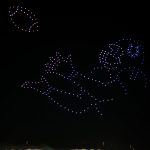 Ein nächtlicher Himmel über einem Berliner Stadion zeigt Hunderte von bunten Drohnen, die den Umriss eines Colts-Footballspielers bilden, der einen Football fangen will, beides in blauem und weißem Licht. Das beleuchtete Stadion und der dunkle Himmel bilden eine eindrucksvolle Drohnenshow-Kulisse. Diese Beschreibung wurde mit der FootballR KI automatisch generiert.