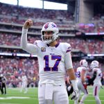 Josh Allen - Woche 11 - Ein Footballspieler im weißen Trikot der Buffalo Bills mit der Nummer 17 steht mitten im Spiel auf dem Feld und hebt die rechte Hand. In diesem Rückblick tragen das überfüllte Stadion und die Anwesenheit des Spielers der Woche zu einer spannenden Atmosphäre bei. Diese Beschreibung wurde mit der FootballR KI automatisch generiert.