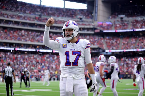 Josh Allen - Woche 11 - Woche 15 - Ein Footballspieler im weißen Trikot der Buffalo Bills mit der Nummer 17 steht mitten im Spiel auf dem Feld und hebt die rechte Hand. In diesem Rückblick tragen das überfüllte Stadion und die Anwesenheit des Spielers der Woche zu einer spannenden Atmosphäre bei. Diese Beschreibung wurde mit der FootballR KI automatisch generiert.