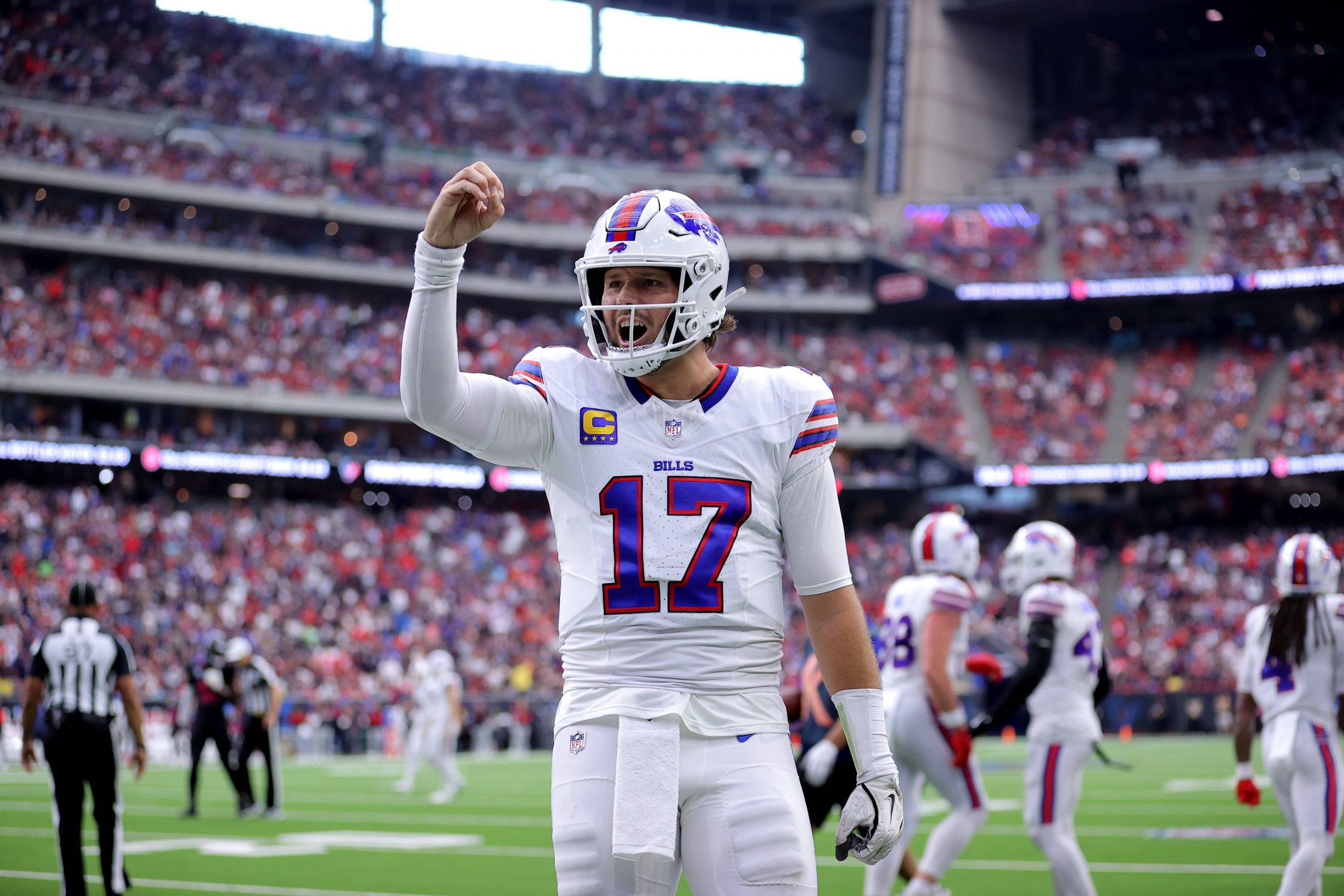 Josh Allen - Woche 11 - Ein Footballspieler im weißen Trikot der Buffalo Bills mit der Nummer 17 steht mitten im Spiel auf dem Feld und hebt die rechte Hand. In diesem Rückblick tragen das überfüllte Stadion und die Anwesenheit des Spielers der Woche zu einer spannenden Atmosphäre bei. Diese Beschreibung wurde mit der FootballR KI automatisch generiert.