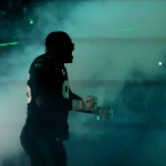 Ein Football-Spieler in voller Montur steht im Profil, schreit oder jubelt inmitten von dichtem Rauch und dramatischer grüner Beleuchtung; die intensive Atmosphäre deutet auf die Energie eines Spiels der Dallas Cowboys hin, mit undeutlichen Figuren und grünen Laserlichtern im Hintergrund. Diese Beschreibung wurde mit der FootballR KI automatisch generiert.