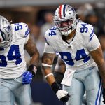 Zwei Footballspieler der Dallas Cowboys in weißen Trikots und silbernen Hosen feiern auf dem Spielfeld. Marshawn Kneeland, der NFL-Talent zeigt, ballt die Faust und schreit, während die verschwommene Menge im Hintergrund brüllt. Diese Beschreibung wurde mit der FootballR KI automatisch generiert.