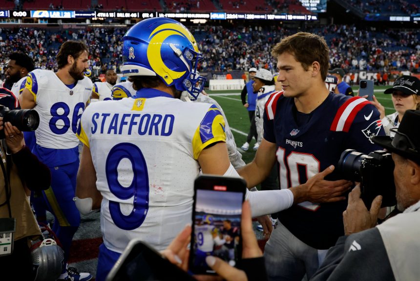 MVP - Ein Rams-Spieler in einem blau-gelben Matthew STAFFORD 9-Trikot schüttelt Drake Maye, der die Nummer 10 der Patriots trägt, auf dem Football-Feld die Hand - ein Moment zwischen den NFL-Award-Finalisten inmitten von Spielern, Medien, Fans und einer Stadionkulisse. Diese Beschreibung wurde mit der FootballR KI automatisch generiert.