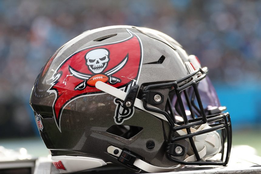 Fünf Trainer mussten gehen - Eine Nahaufnahme eines Footballhelms der Tampa Bay Buccaneers zeigt ein silbernes und rotes Design mit dem ikonischen Piratenflaggen-Logo. Der Helm, der mit Cheftrainer Bowles verbunden ist, ruht auf einer Fläche mit einem unscharfen Stadionhintergrund. Diese Beschreibung wurde mit der FootballR KI automatisch generiert.