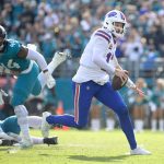 Ein Spieler der Buffalo Bills in einer weißen Uniform rennt mit dem Ball, verfolgt von einem Verteidiger der Jaguars in Grün. Das sonnenbeschienene Spielfeld und die verschwommenen Zuschauer fangen den Nervenkitzel eines Last-Minute-Dramas ein, das sich mitten im Spiel abspielt. Diese Beschreibung wurde mit der FootballR KI automatisch generiert.