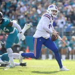 Wildcard Weekend - Ein Spieler der Buffalo Bills in einer weißen Uniform rennt mit dem Ball, verfolgt von einem Verteidiger der Jaguars in Grün. Das sonnenbeschienene Spielfeld und die verschwommenen Zuschauer fangen den Nervenkitzel eines Last-Minute-Dramas ein, das sich mitten im Spiel abspielt. Diese Beschreibung wurde mit der FootballR KI automatisch generiert.