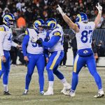 Vier Footballspieler der Los Angeles Rams in blau-weißen Trikots feiern auf einem verschneiten Feld während des NFC Championship Games; einer umarmt den Kicker, während die Nummer 85 (Allen) beide Arme zum Sieg erhebt, während die Zuschauer von der Tribüne aus zusehen. Diese Beschreibung wurde mit der FootballR KI automatisch generiert.