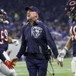 Drei Footballspieler der Chicago Bears in Spielkleidung stehen auf dem Spielfeld mit Trainer John Fox, der während eines Spiels Anweisungen zu geben scheint. Alt-Text wurde KI-generiert.
