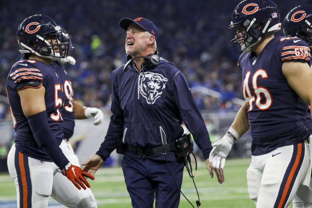 Drei Footballspieler der Chicago Bears in Spielkleidung stehen auf dem Spielfeld mit Trainer John Fox, der während eines Spiels Anweisungen zu geben scheint. Alt-Text wurde KI-generiert.