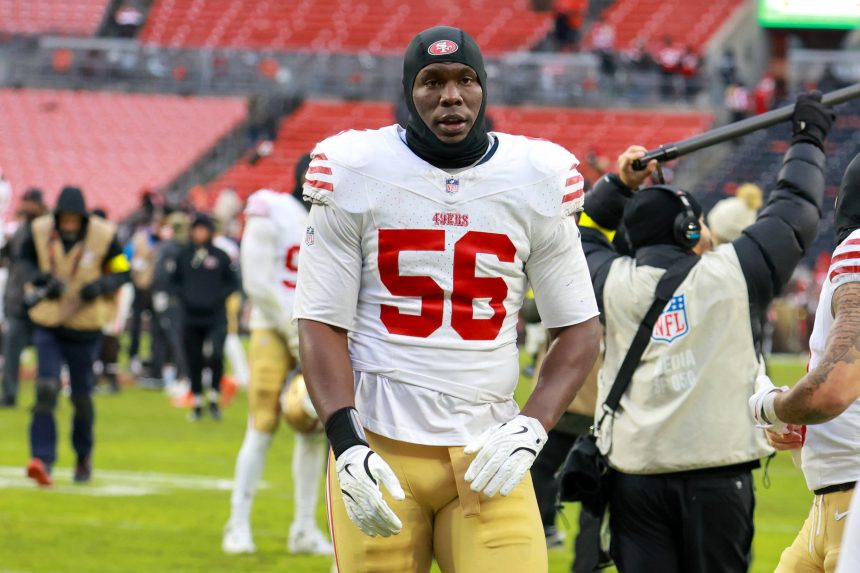 Keion White - Ein Footballspieler, der ein weiß-rotes 49ers-Trikot mit der Nummer 56 trägt, steht nach einem Spiel auf dem Feld und erinnert an Keion Whites entschlossenes Auftreten. Alt-Text wurde KI-generiert.