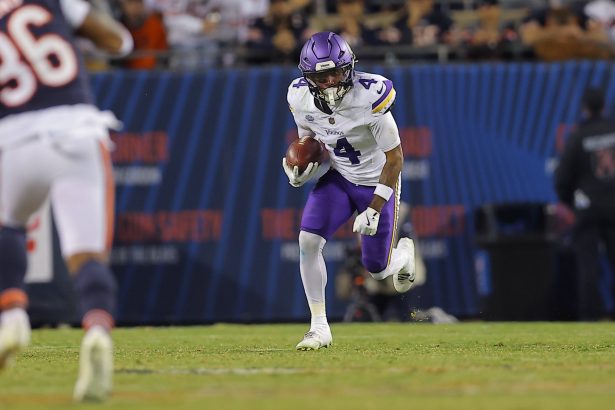 Rondale Moore - Ein Receiver der Minnesota Vikings in einem weiß-lila Trikot läuft während eines Spiels auf dem NFL-Feld mit dem Ball, während im Hintergrund gegnerische Spieler zu sehen sind. Alt-Text wurde KI-generiert.