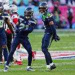 Super Bowl LX - Die Spieler der Seattle Seahawks feiern während eines Footballspiels auf dem Spielfeld und zeigen ihre starke Verteidigung, während im Hintergrund Spieler der New England Patriots zu sehen sind. Alt-Text wurde KI-generiert.
