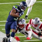 Kenneth Walker III von den Seattle Seahawks rennt mit dem Football, während zwei Verteidiger der New England Patriots versuchen, ihn während eines NFL-Spiels zu tackeln. Dabei zeigt er Fähigkeiten, die eines Super Bowl LX MVP-Anwärters würdig sind. Alt-Text wurde KI-generiert.