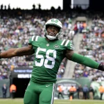 Darron Lee, Linebacker der New York Jets, trägt die Nummer 58 und steht während eines Spiels mit ausgestreckten Armen auf dem Spielfeld. Alt-Text wurde KI-generiert.
