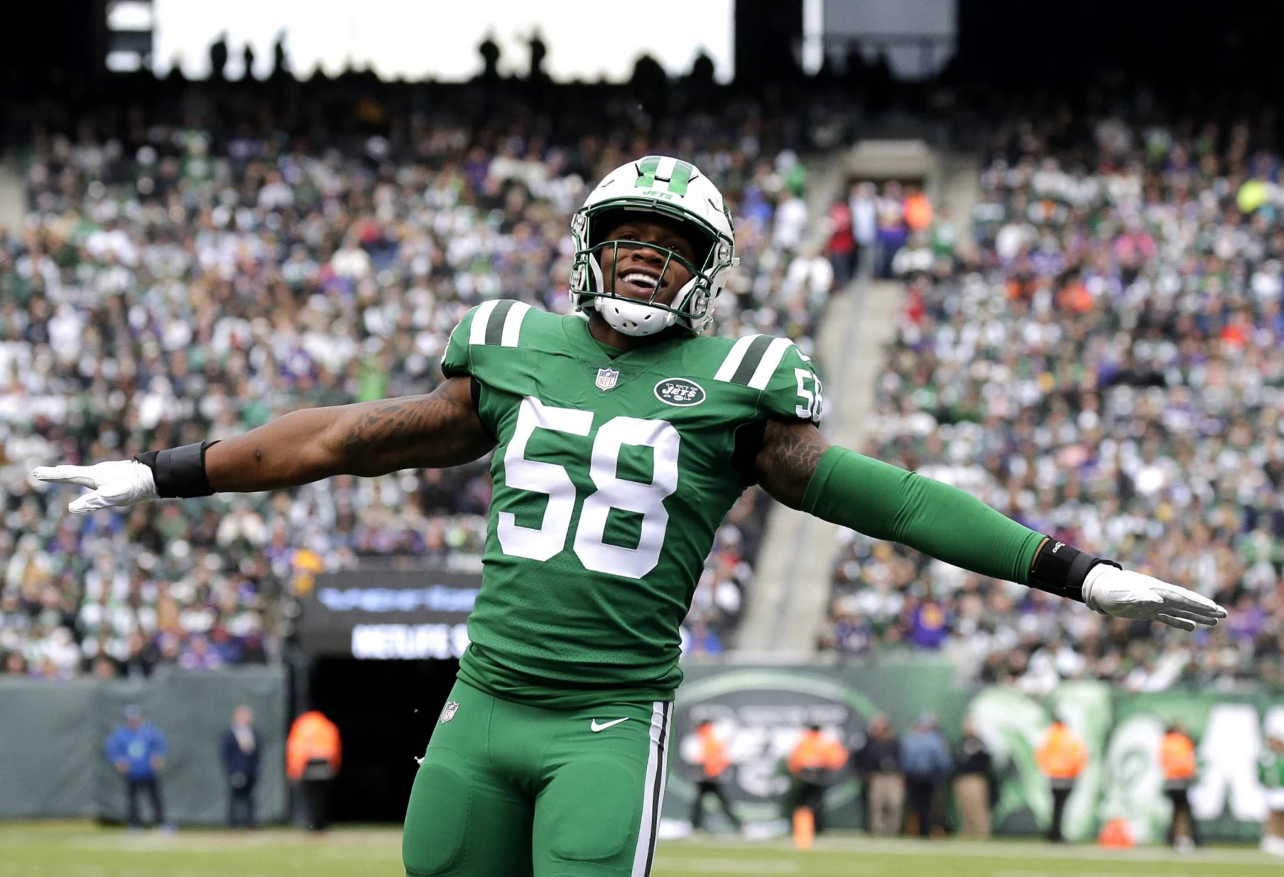 Darron Lee, Linebacker der New York Jets, trägt die Nummer 58 und steht während eines Spiels mit ausgestreckten Armen auf dem Spielfeld. Alt-Text wurde KI-generiert.