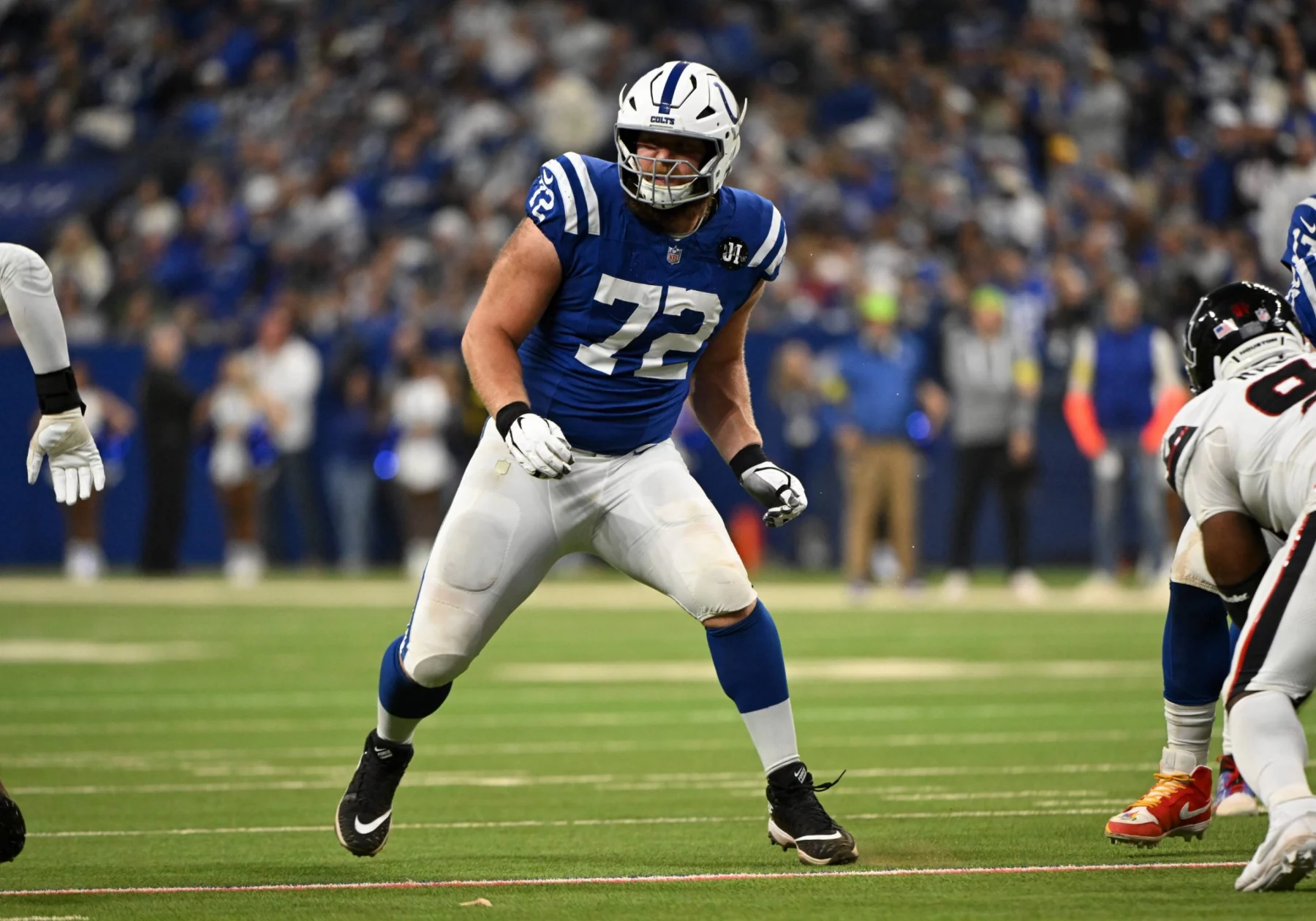 Braden Smith - Offensive Tackle im blauen Trikot der Indianapolis Colts, Nummer 72, bereitet sich während eines Spiels auf einem grünen Feld mit einer Menschenmenge im Hintergrund auf den Block vor; er wird 2026 in die Free Agency eintreten. Alt-Text wurde KI-generiert.
