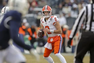 Quarterback in weiß-orange Trikot mit Ball in der Hand beim NCAA Football Spiel Clemson gegen Penn State im Pinstripe Bowl 2025