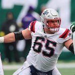 Ein Offensive Lineman der Patriots in einem weißen Trikot blockt einen Verteidiger der New York Jets während eines Footballspiels und zeigt dabei Fähigkeiten, die an Garrett Bradbury erinnern. Alt-Text wurde KI-generiert.