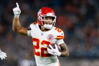 Chiefs-Star Trent McDuffie, der die Nummer 22 trägt, läuft mit dem Ball und zeigt nach oben während eines intensiven Spiels gegen die Rams. Alt-Text wurde KI-generiert.