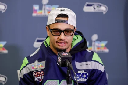 Jaxon Smith-Njigba mit Seahawks-Jersey und weißer Kappe spricht bei Pressekonferenz vor Super Bowl LX Hintergrund