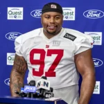 Der Spieler der New York Giants, Dexter Lawrence (Nummer 97), steht während einer Presseveranstaltung an einem Podium mit Mikrofonen und diskutiert möglicherweise über die Spielzüge des Teams im Vorfeld des NFL Draft 2026. Alt-Text wurde KI-generiert.