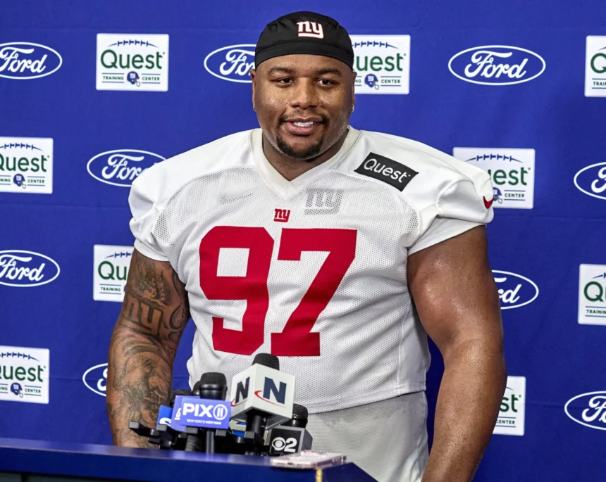 Der Spieler der New York Giants, Dexter Lawrence (Nummer 97), steht während einer Presseveranstaltung an einem Podium mit Mikrofonen und diskutiert möglicherweise über die Spielzüge des Teams im Vorfeld des NFL Draft 2026. Alt-Text wurde KI-generiert.