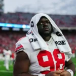 NFL Draft 2026 in Aussicht: Ein Defensive Tackle mit der Trikotnummer 98 steht mit einem Handtuch über dem Kopf auf dem Spielfeld, im Hintergrund sind die Tribünen zu sehen. Alt-Text wurde KI-generiert.
