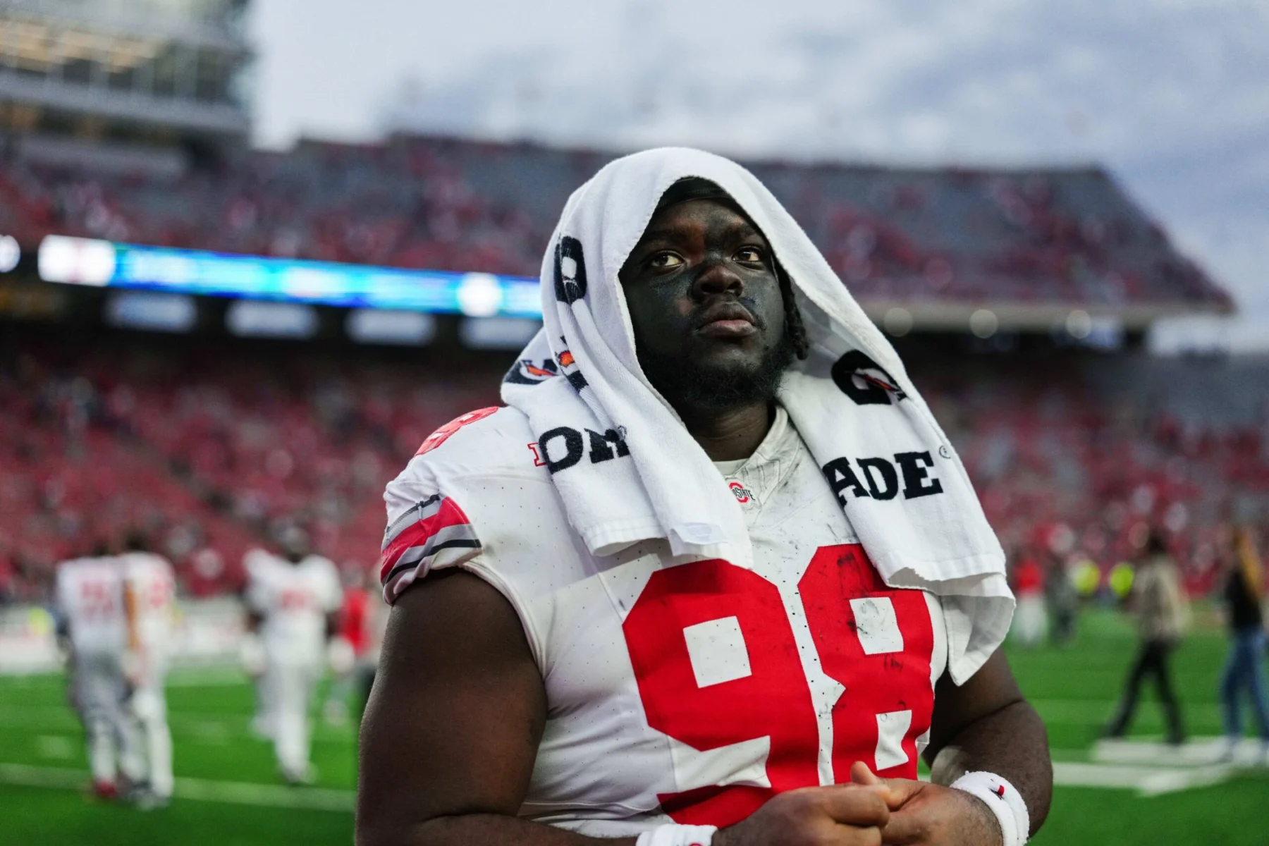 NFL Draft 2026 in Aussicht: Ein Defensive Tackle mit der Trikotnummer 98 steht mit einem Handtuch über dem Kopf auf dem Spielfeld, im Hintergrund sind die Tribünen zu sehen. Alt-Text wurde KI-generiert.