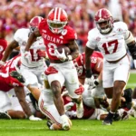 RB Kaelon Black, ein herausragender College-Football-Spieler aus Indiana, läuft mit dem Ball, während Verteidiger von Alabama ihn während eines Spiels verfolgen. Im Hintergrund sind Spieler und Schiedsrichter zu sehen, die sein Potenzial für den NFL-Draft 2026 unterstreichen. Alt-Text wurde KI-generiert.
