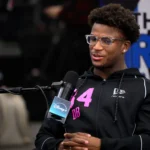 Caleb Downs - Ein Mann mit Brille und schwarzem Kapuzenpulli mit der Nummer 34 sitzt in einer Studioumgebung und spricht in ein Mikrofon mit der Aufschrift "Disney+", um über Safeties und ihre Aussichten für den NFL Draft 2026 zu sprechen. Alt-Text wurde KI-generiert.