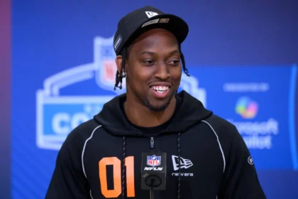 Ein Mann in einem schwarzen NFL-Kapuzenpulli und einer Mütze spricht an einem Mikrofon mit einem NFL Draft 2026 im Hintergrund, möglicherweise über Kaytron Allens Spielerprofil. Alt-Text wurde KI-generiert.