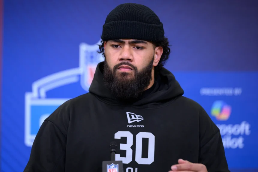 Ein Mann mit Bart und schwarzer Mütze, der einen schwarzen Kapuzenpulli mit der Nummer 30 trägt, steht bei einer Veranstaltung vor einer Kulisse für den NFL Draft 2026. Alt-Text wurde KI-generiert.