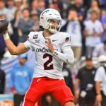 Der Footballspieler der Cincinnati Bearcats, Brendan Sorsby (weißes Trikot mit der Nummer 2), bereitet sich während eines Spiels auf einen Pass vor, im Hintergrund ist das Publikum zu sehen – ein potenzieller Kandidat für den NFL Supplemental Draft 2026. Alt-Text wurde KI-generiert.
