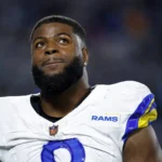 Jared Verse: Ein NFL-Spieler der Los Angeles Rams, der ein weiß-blaues Trikot trägt, blickt während eines Spiels nach oben. Alt-Text wurde KI-generiert.