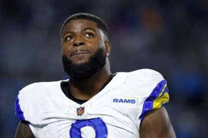 Jared Verse: Ein NFL-Spieler der Los Angeles Rams, der ein weiß-blaues Trikot trägt, blickt während eines Spiels nach oben. Alt-Text wurde KI-generiert.