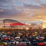 Ein großes Stadion mit roten Akzenten, die Heimstätte der Kansas City Chiefs, ist umgeben von einem überfüllten Parkplatz voller Autos und Tailgating-Zelten unter einem teilweise bewölkten Abendhimmel. Alt-Text wurde KI-generiert.