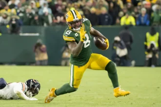 Josh Jacobs - Ein Spieler der Green Bay Packers läuft mit dem Football davon, während ein Verteidiger der Chicago Bears hinter ihm zurückbleibt – und das gerade in dem Moment, in dem die NFL Jacobs auf die Liste der Schlüsselspieler setzt. Alt-Text wurde KI-generiert.