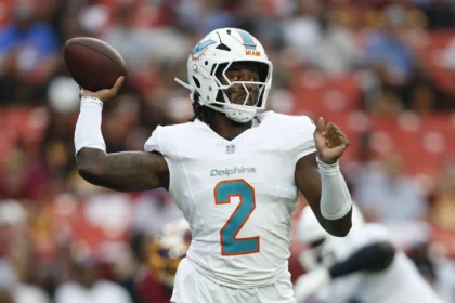 Malik Willis - Ein Footballspieler der Miami Dolphins in weißem Trikot und Helm macht sich während eines Spiels gegen die Commanders bereit, den Football zu werfen. Alt-Text wurde KI-generiert.