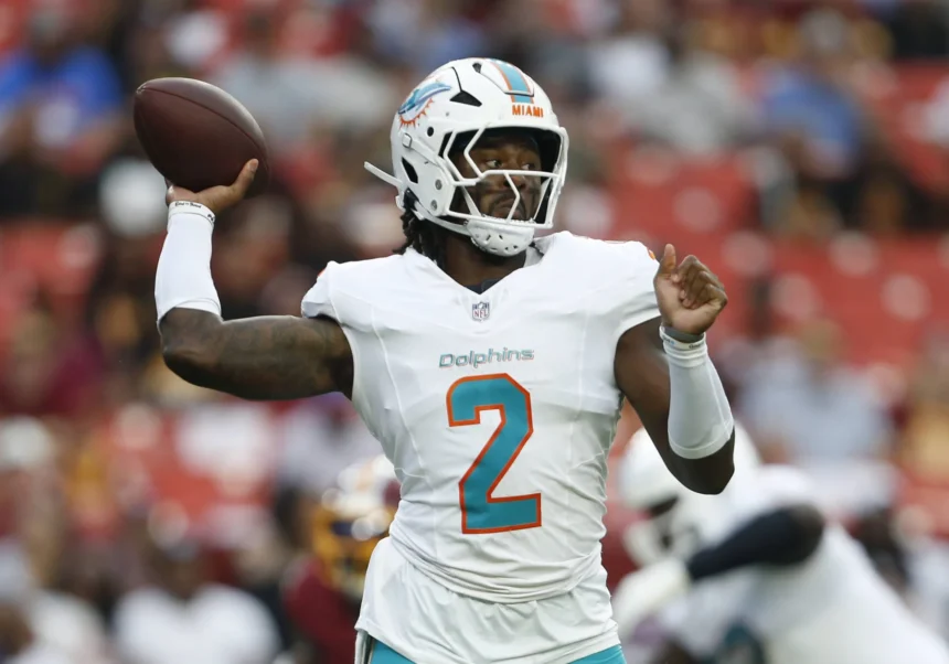 Malik Willis - Ein Footballspieler der Miami Dolphins in weißem Trikot und Helm macht sich während eines Spiels gegen die Commanders bereit, den Football zu werfen. Alt-Text wurde KI-generiert.