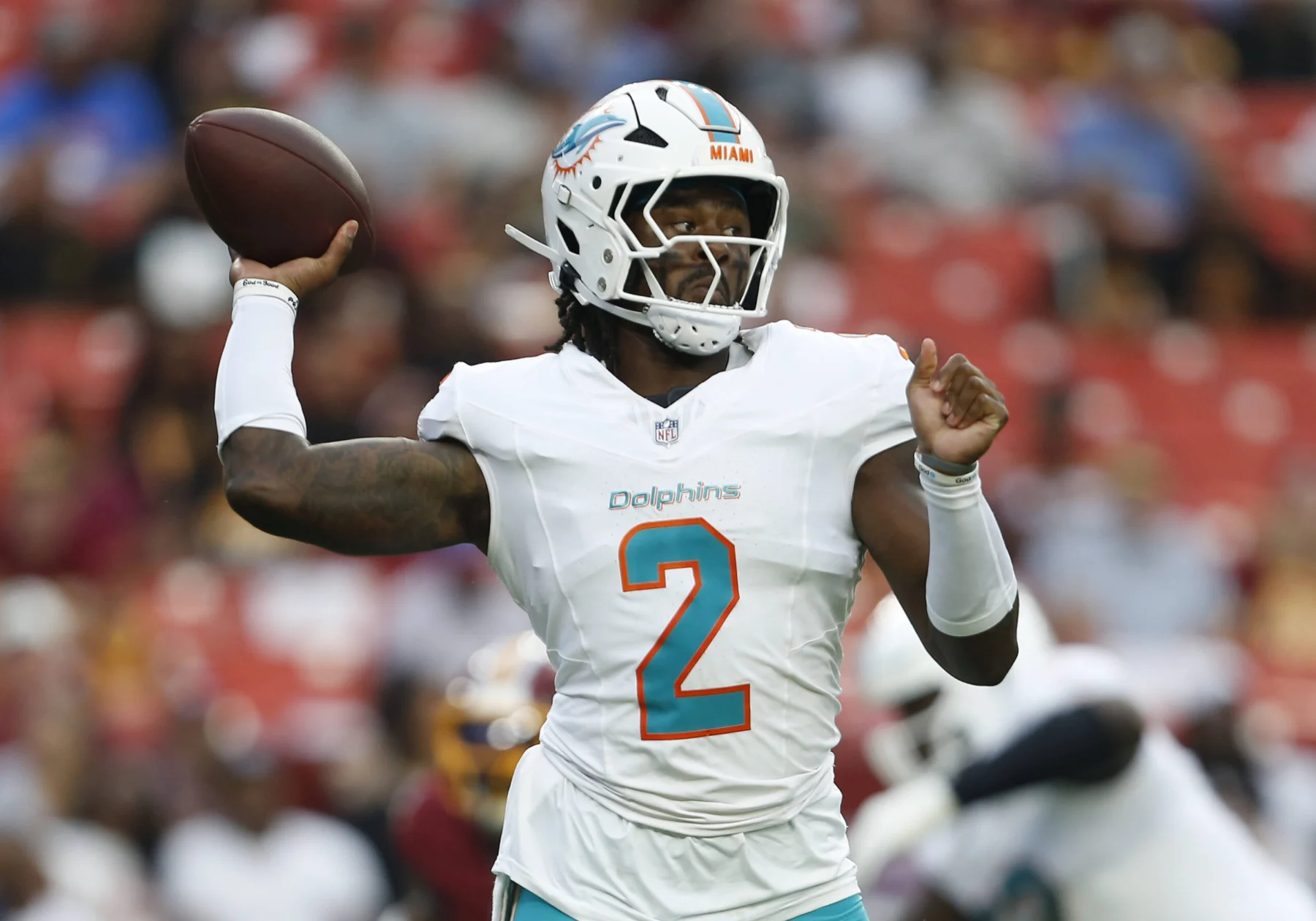 Malik Willis - Ein Footballspieler der Miami Dolphins in weißem Trikot und Helm macht sich während eines Spiels gegen die Commanders bereit, den Football zu werfen. Alt-Text wurde KI-generiert.