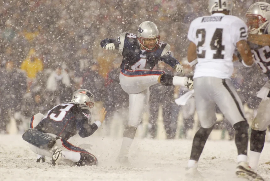 Adam Vinatieri - Ein Footballspieler zeigt die Präzision eines Adam Vinatieri, als er während eines verschneiten Spiels im Schatten der Alpen ein Field Goal schießt, während seine Teamkollegen den Ball halten und die gegnerischen Spieler versuchen, den Schuss zu blocken. Alt-Text wurde KI-generiert.