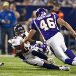 Alphonso Smith - Ein Spieler der Denver Broncos wird während eines Footballspiels von einem ehemaligen Spieler der Minnesota Vikings mit der Trikotnummer 46 zu Boden gebracht. Alt-Text wurde KI-generiert.